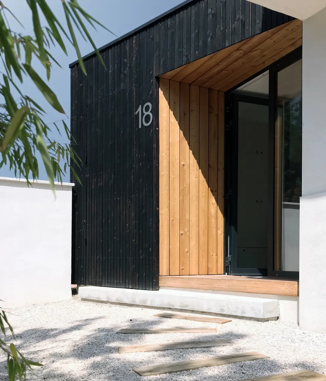 Extension en bois brûlé à Lyon, entrée protégée de la maison années 50 rénovée