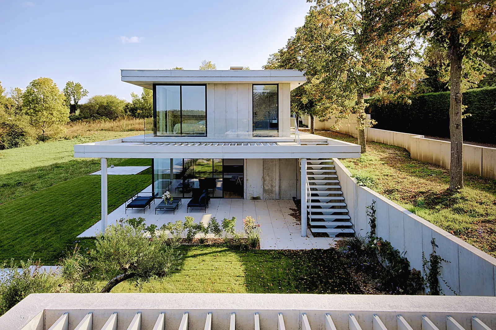 Vue d'ensemble de la maison de Tassin sur deux niveaux, terrasse couverte du rez-de-jardin et escalier extérieur